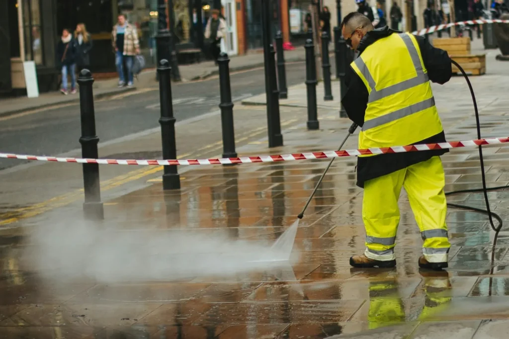 Technician pressure washing a city sidewalk