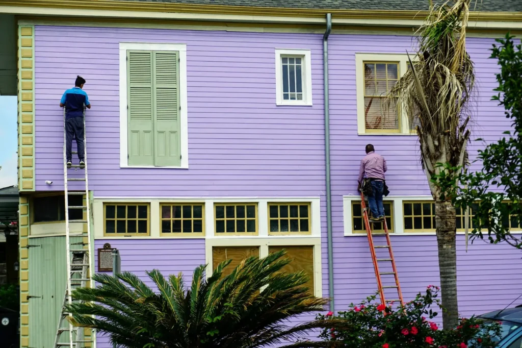 Painters on ladders painting a house exterior