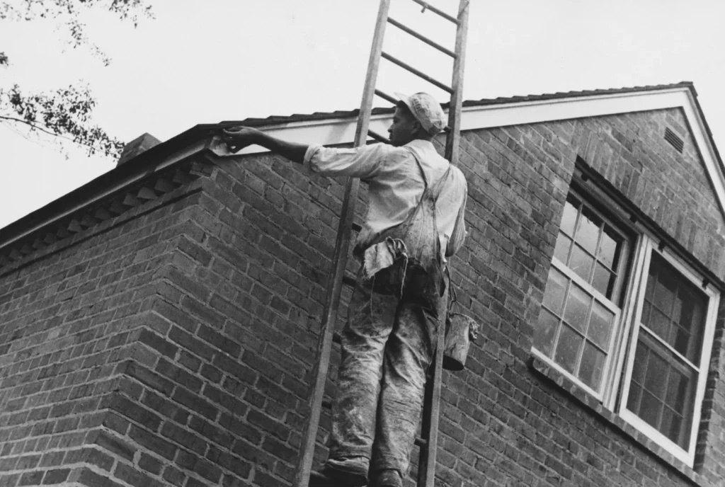 Painter on a ladder at a brick house