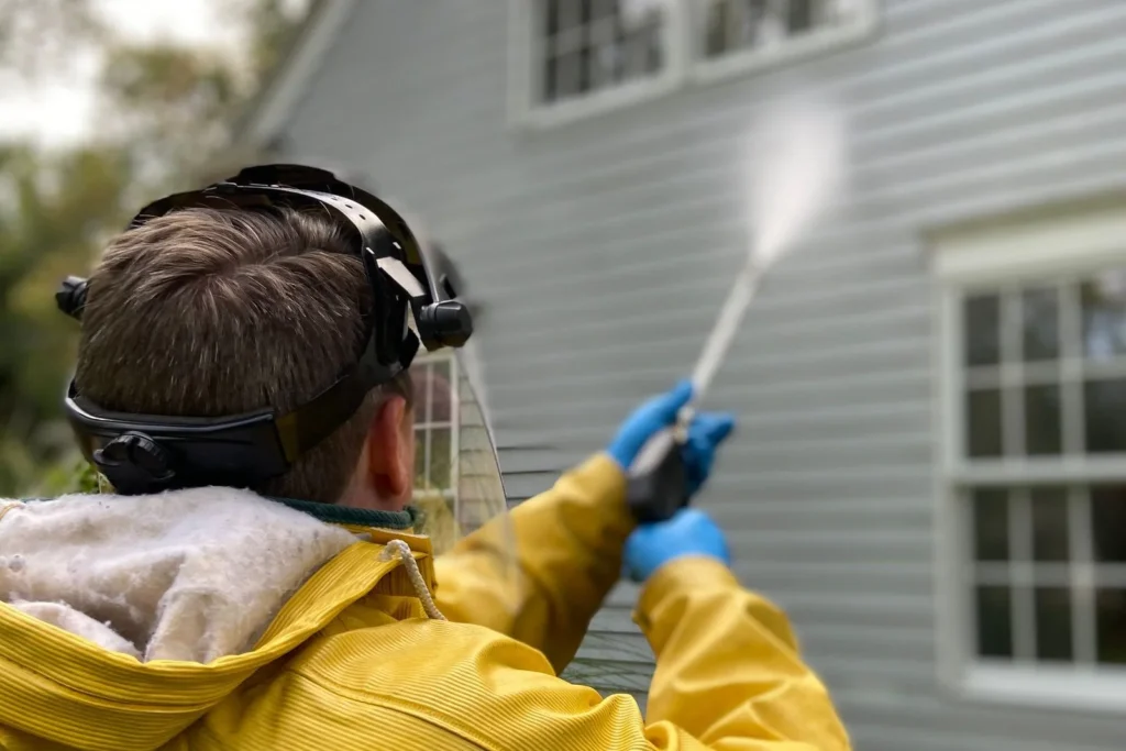 Worker pressure washing house siding