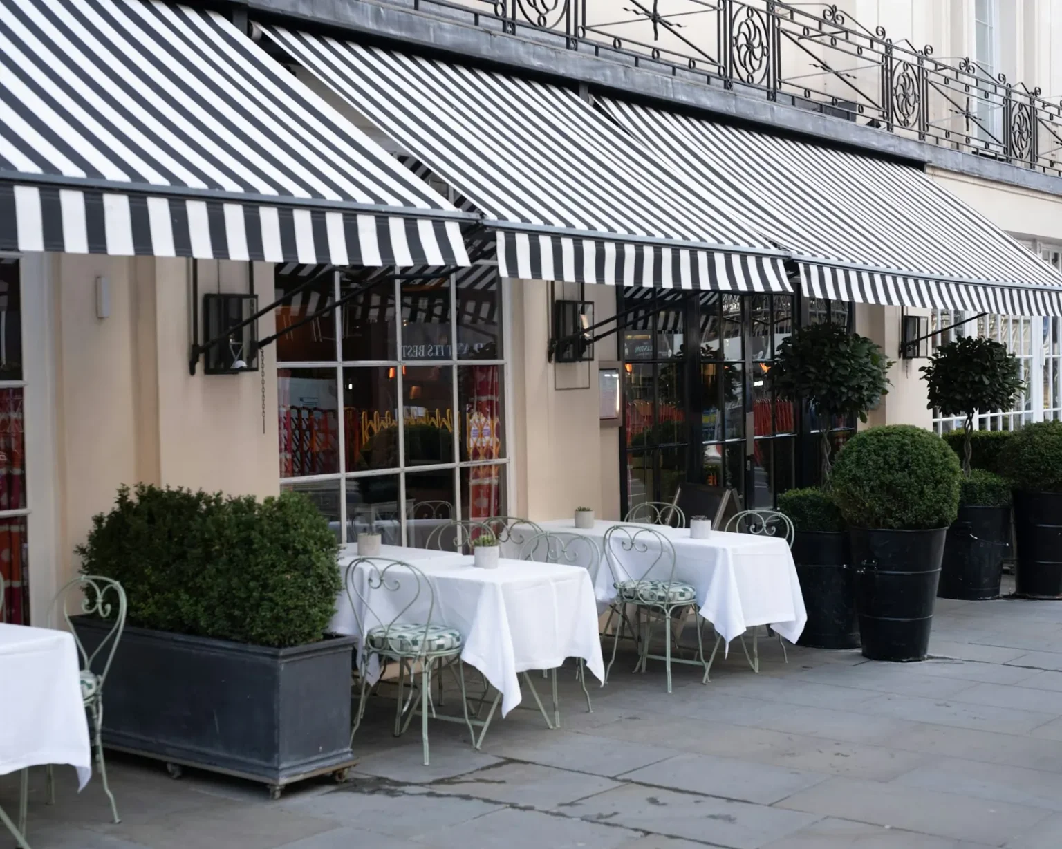 Black and white striped fabric awnings shading a cafe patio